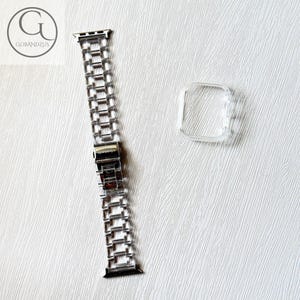 May include: A silver-toned metal link watch band featuring a rectangular clasp mechanism, accompanied by a separate clear, transparent protective bumper case designed to fit around the square housing of a digital smartwatch.