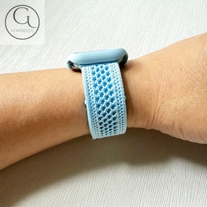 May include: A light blue watch strap with a woven pattern is displayed on a wrist. The strap is connected to a light blue watch face. The strap features a repeating open weave design. The logo "GOBANDZUS" is in the upper left corner.