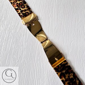 Puede incluir: Una correa de reloj dorada con estampado de leopardo. La correa est&aacute; hecha de un material duradero y cuenta con un cierre seguro.