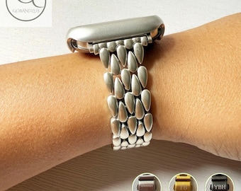 May include: A silver-toned metal watch band featuring a multi-row teardrop link design. The band is attached to a watch casing. Three small circular insets at the bottom display the band in bronze, gold, and black with custom engraving options.