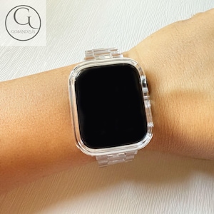 May include: A clear, transparent smartwatch band and protective case set featuring a link-style bracelet design. The watch face is black and rectangular with rounded corners, encased in a matching transparent frame that secures the device.