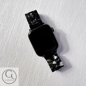 May include: Black Apple Watch with a black and white marbled watch band.