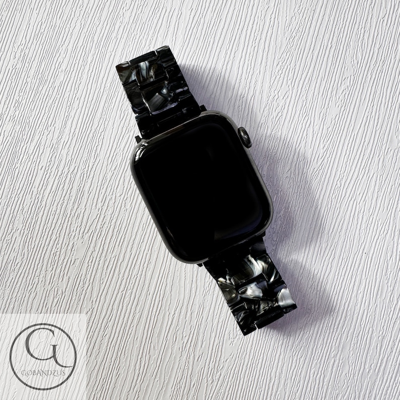 May include: Black Apple Watch with a black and white marbled watch band.