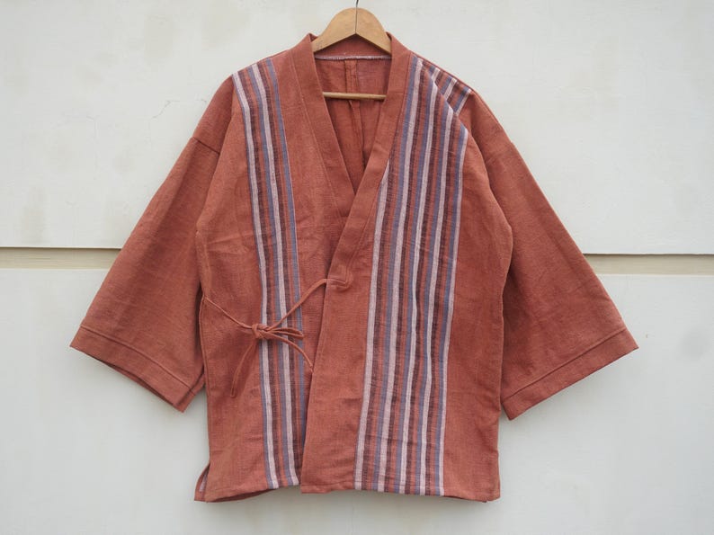 Puede incluir: Chaqueta estilo kimono de color &oacute;xido con cuello en V y mangas cortas. La parte delantera presenta rayas verticales en tonos blancos, morados y azules. Un cierre de lazo a juego est&aacute; en la cintura.