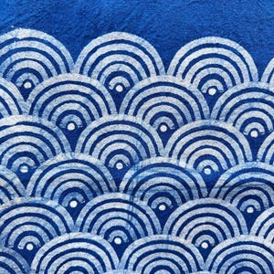K&ouml;nnte beinhalten: Nahaufnahme eines blauen Stoffes mit einem sich wiederholenden Muster aus wei&szlig;en, konzentrischen Halbkreisen. Das Design erinnert an stilisierte Wellen oder B&ouml;gen und erzeugt einen strukturierten, geschichteten Effekt. Der Hintergrund ist einfarbig, tiefblau.