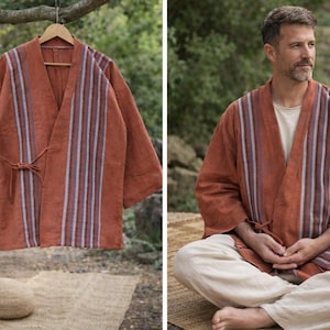 Puede incluir: Bata estilo kimono de color &oacute;xido con detalles de rayas verticales en blanco, morado y azul. La bata se muestra en una percha de madera y la lleva una persona. La bata tiene un cierre de lazo y mangas anchas. La tela es suave y fluida.