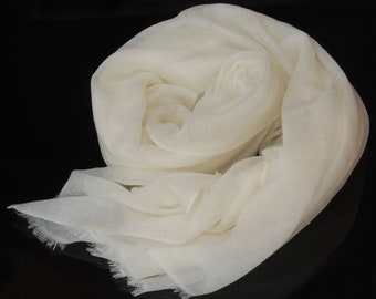 May include: A soft, white, sheer scarf made of delicate fabric. The scarf is folded and draped on a black surface.