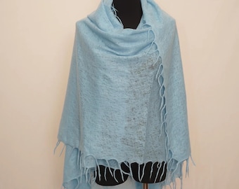 May include: A light blue shawl with fringe detail, displayed on a mannequin. The soft, woven fabric drapes elegantly, creating a flowing silhouette. The shawl is a solid color, perfect for adding a touch of color to any outfit.