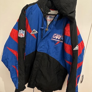 Könnte beinhalten: Eine blaue, schwarze und rote Vintage-Jacke mit Kapuze. Die Jacke zeigt das NFL-Logo und das Wort "GIANTS" auf der Vorderseite. Die Ärmel haben rote Streifen. Die Jacke wird von Apex hergestellt.