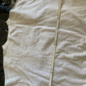 K&ouml;nnte beinhalten: Ein graues Sweatshirt mit einem Ma&szlig;band, das &uuml;ber den R&uuml;cken gelegt ist. Das Band misst 71 cm.