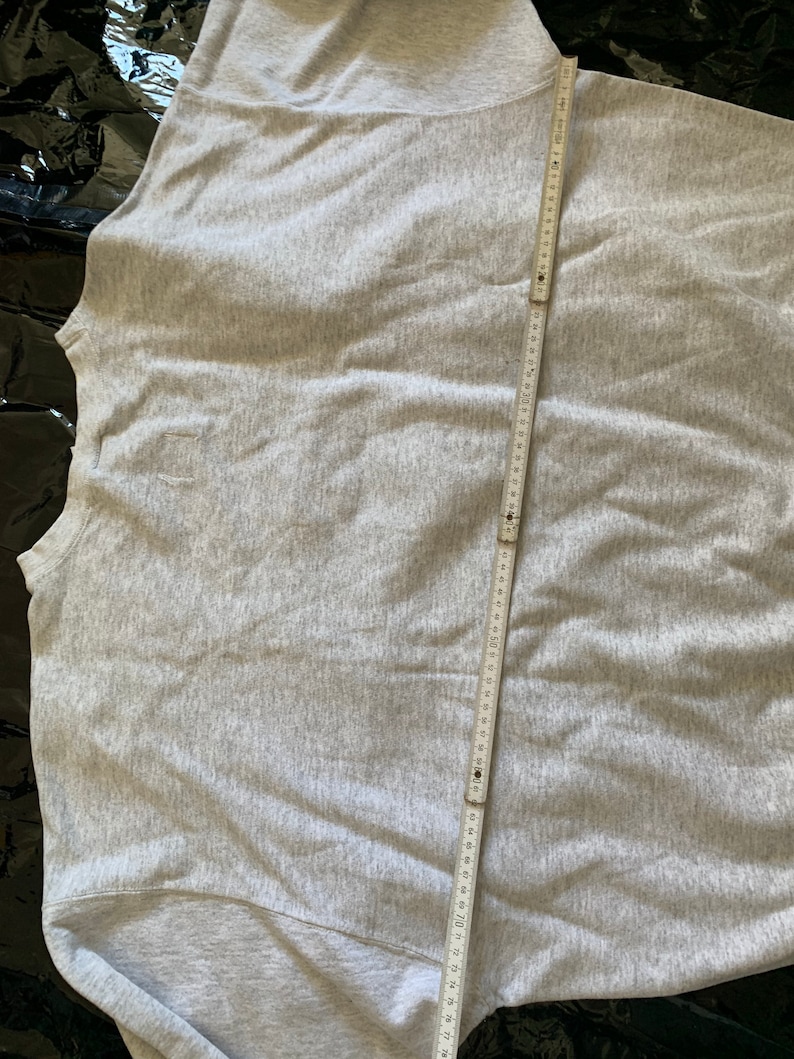 K&ouml;nnte beinhalten: Ein graues Sweatshirt mit einem Ma&szlig;band, das &uuml;ber den R&uuml;cken gelegt ist. Das Band misst 71 cm.