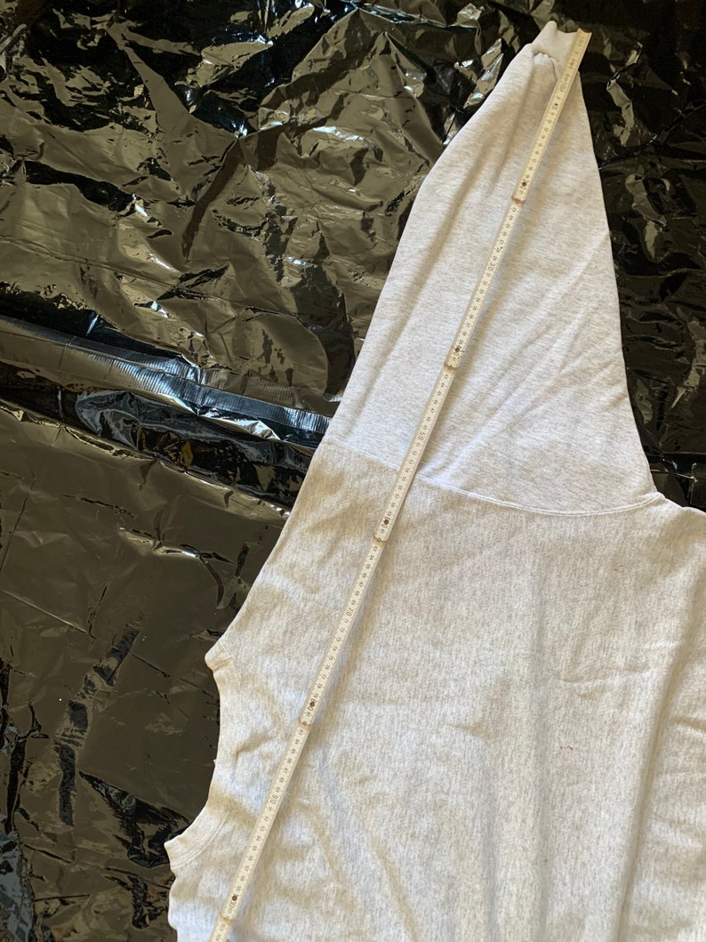 K&ouml;nnte beinhalten: Ein grauer Kapuzenpullover mit einem langen &Auml;rmel. Der &Auml;rmel liegt flach und wird mit einem Lineal gemessen.