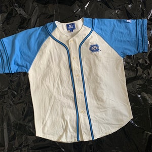 May include: White baseball jersey with blue sleeves and a black and blue striped trim. The jersey has a button-up front and a small embroidered logo on the left chest.