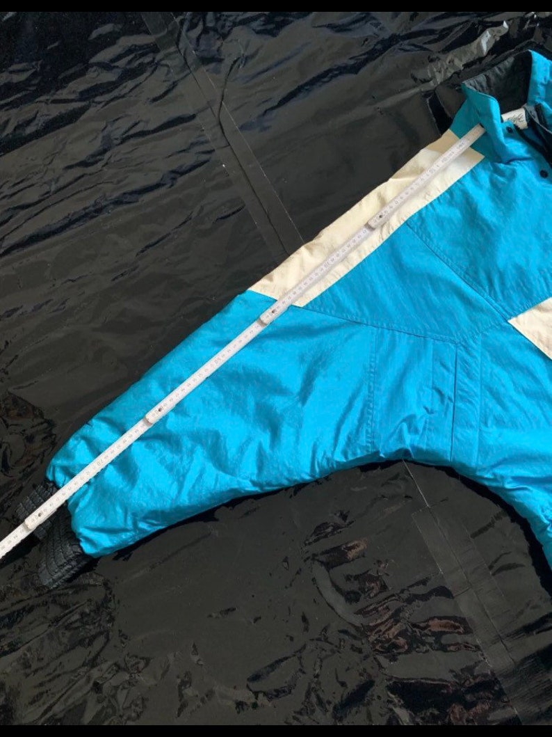 May include: A blue ski jacket with a white stripe down the sleeve. The jacket has a zipper closure and a hood.