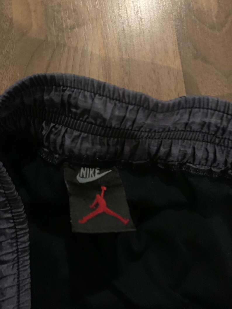 May include: A black Nike Jordan brand label with a white Nike swoosh and a red Jumpman logo.