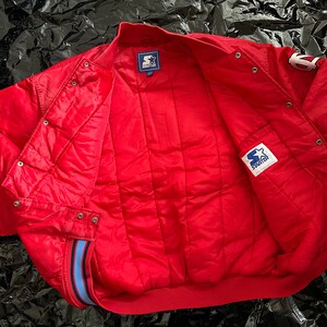 May include: Red Starter brand bomber jacket with blue and white trim. The jacket has a quilted lining and a snap closure.