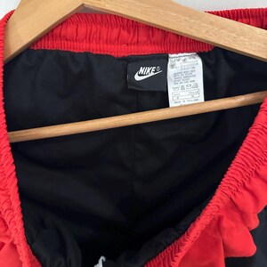 May include: Black and red Nike athletic shorts with a white drawstring. The tag reads "Nike" and "Made in Thailand".