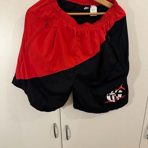 May include: Black and red athletic shorts with a white Nike logo and a red and white graphic on the right leg that says "Air Jordan".
