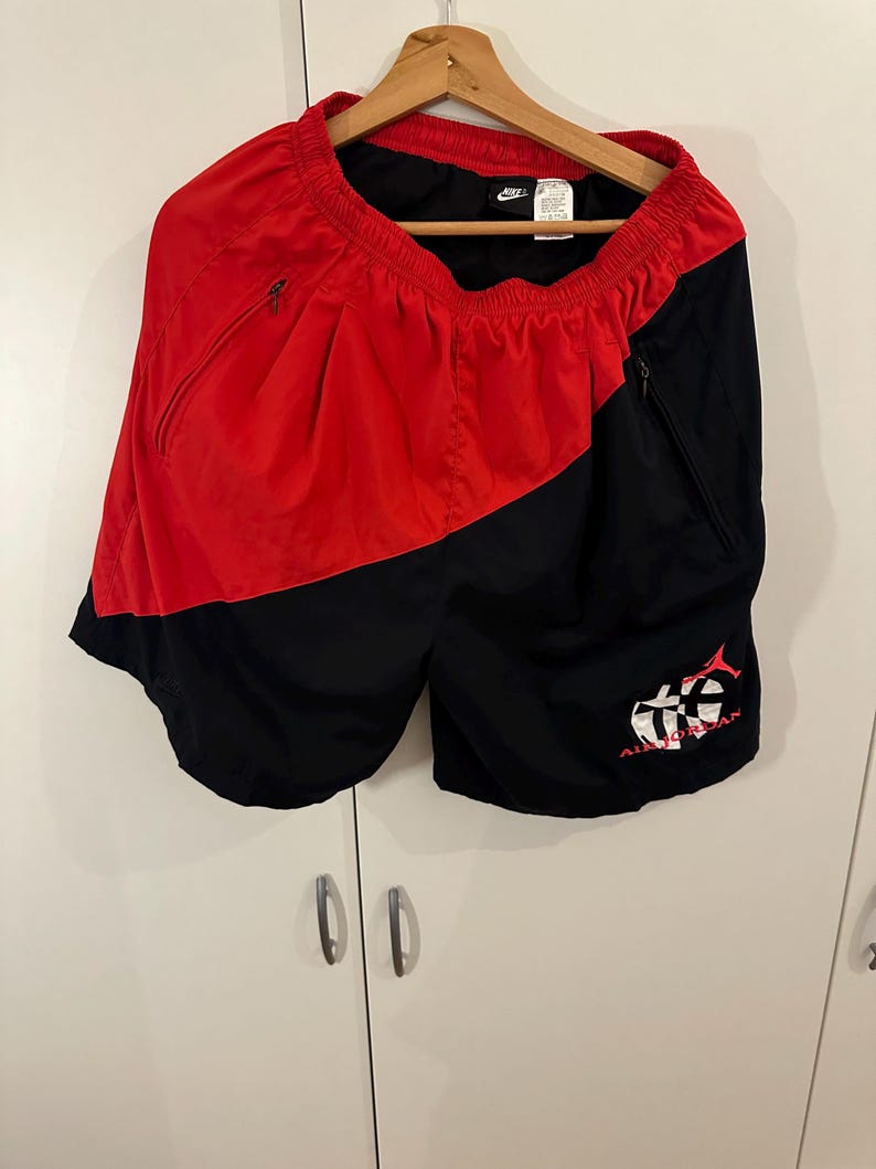 May include: Black and red athletic shorts with a white Nike logo and a red and white graphic on the right leg that says "Air Jordan".