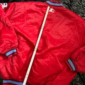 May include: Red satin baseball jacket with blue and black trim. The jacket has a large "STARTER" logo on the back.
