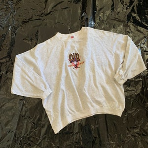 K&ouml;nnte beinhalten: Ein grauer Pullover mit einem schwarzen, orangefarbenen und roten gestickten Motiv eines Basketballspielers mit dem Wort "AIR" &uuml;ber dem Spieler.