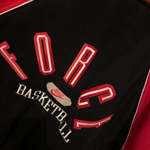 May include: Black and red basketball jacket with the word "FORCE" in red and white lettering. The word "BASKETBALL" is embroidered in white. A Nike logo is visible.