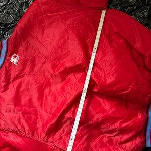 May include: Red satin bomber jacket with a blue and white striped collar and cuffs. The jacket has a white "Starter" logo on the left chest.