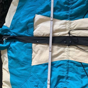 May include: A blue, white, and black jacket with a zipper closure and a drawstring at the waist.