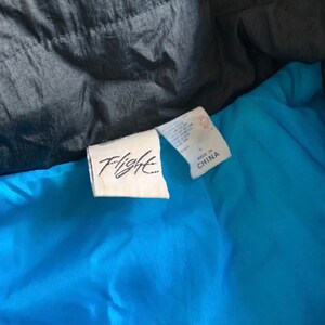 May include: A blue and black jacket with a white tag that says "Flight" and "Made in China".