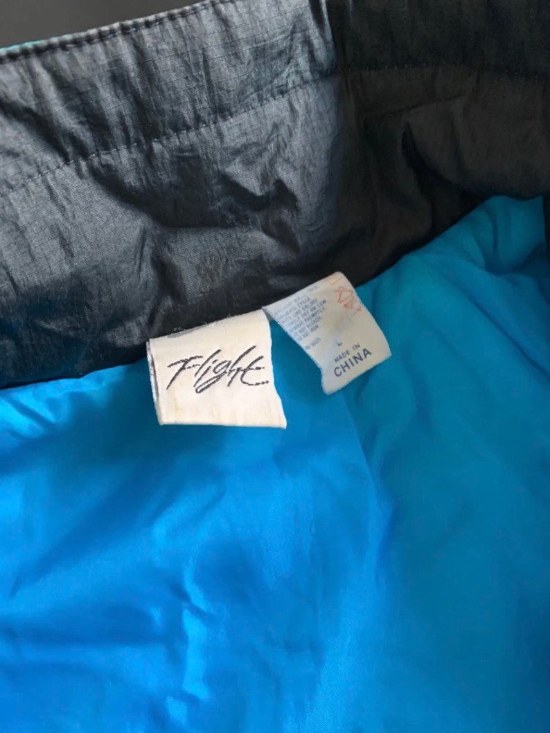 May include: A blue and black jacket with a white tag that says "Flight" and "Made in China".