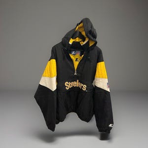 Könnte beinhalten: Schwarz-gelbe Kapuzenjacke mit dem Wort "Steelers" auf der Brust gestickt. Die Jacke hat einen Halb-Reißverschluss und weiße Akzente an den Ärmeln. Das Starter-Logo ist auf dem Ärmel sichtbar.