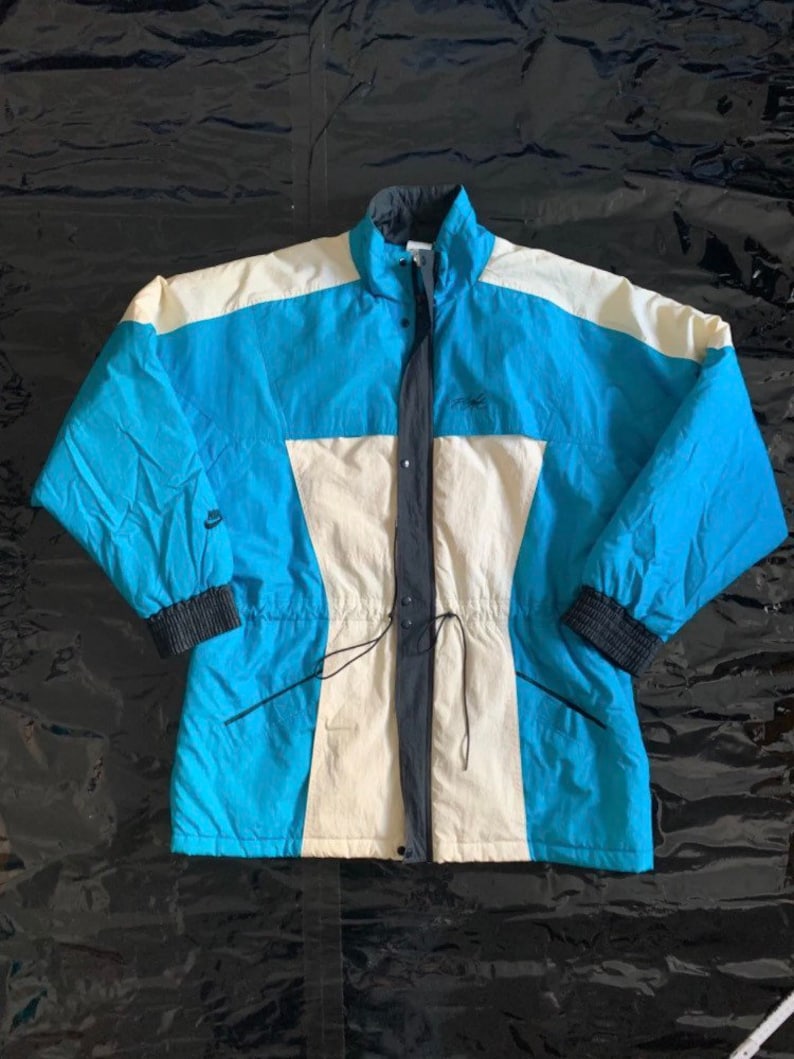 May include: A blue, white, and black vintage Nike jacket with a zipper closure and a drawstring waist.