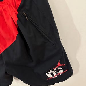 May include: Black and red athletic shorts with a zippered pocket and a red embroidered logo that says "Air Jordan" on the right leg.
