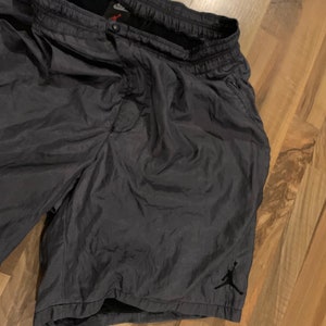 May include: Dark gray athletic shorts with a black Jumpman logo on the right leg. The shorts have a drawstring waistband and side pockets.