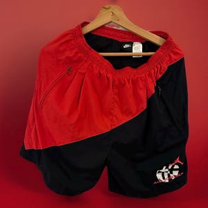May include: Red and black athletic shorts with a white Nike logo and a white "Air Jordan" logo with a basketball and a fish graphic.