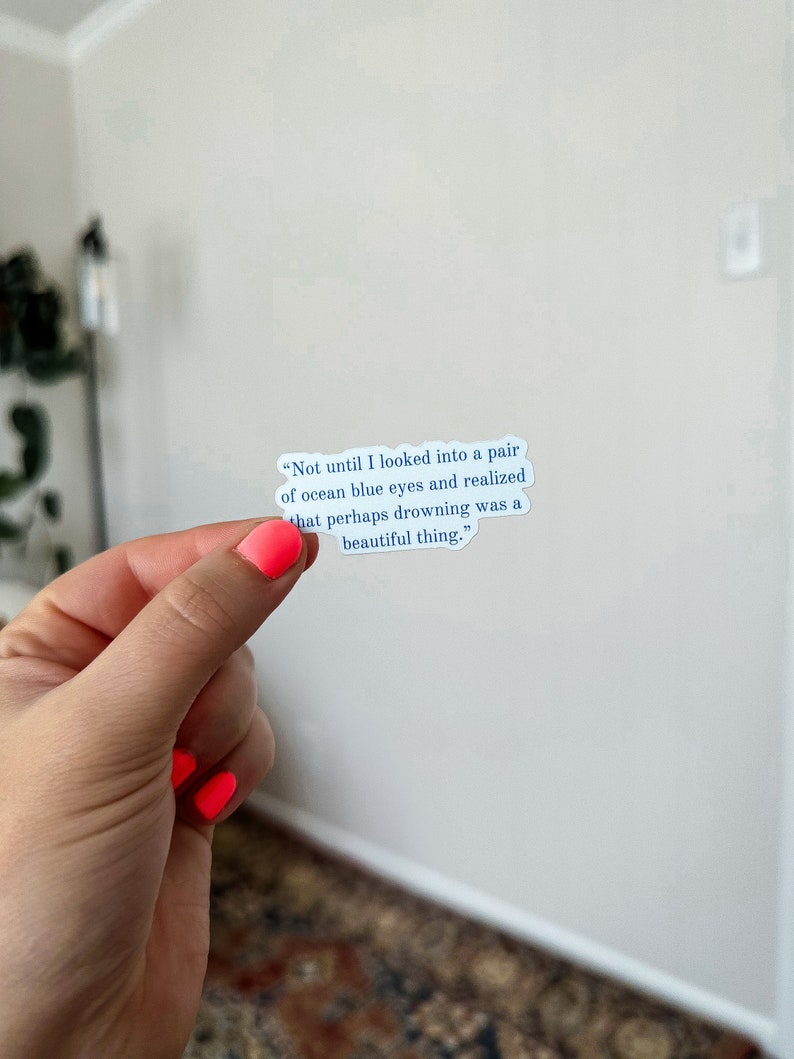 May include: A white sticker with a blue quote that reads "Not until I looked into a pair of ocean blue eyes and realized that perhaps drowning was a beautiful thing."