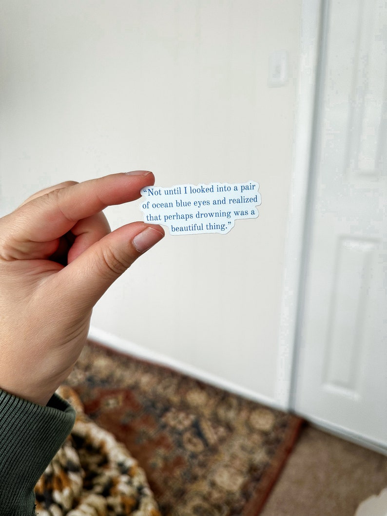 May include: A white sticker with blue text that reads "Not until I looked into a pair of ocean blue eyes and realized that perhaps drowning was a beautiful thing."