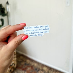 May include: A white sticker with blue text that reads "Not until I looked into a pair of ocean blue eyes and realized that perhaps drowning was a beautiful thing."