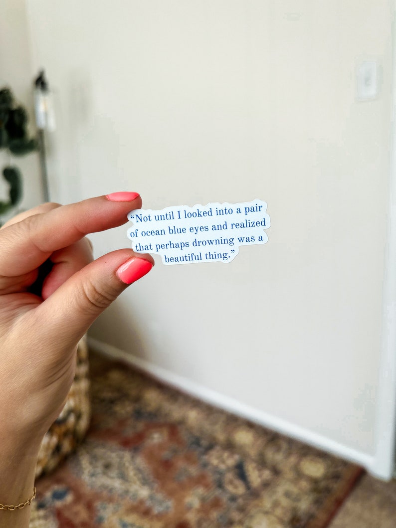 May include: A white sticker with blue text that reads "Not until I looked into a pair of ocean blue eyes and realized that perhaps drowning was a beautiful thing."