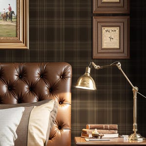 May include: A bedroom scene featuring a tufted brown leather headboard, pillows, and a bedspread. A framed painting of riders on horseback hangs above the bed. A gold-toned lamp and a nightstand with books complete the scene.