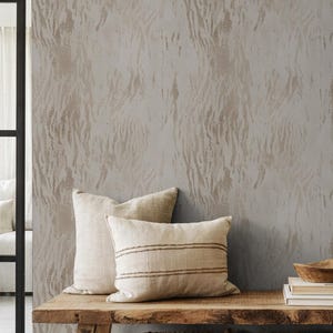 Könnte beinhalten: Neutrale Innenszene mit einer Holzbank, zwei Kissen, einer Holzschale und Büchern. Zwei geflochtene Körbe stehen darunter. Die Wand hat ein strukturiertes, abstraktes Muster in Beige- und Grautönen.