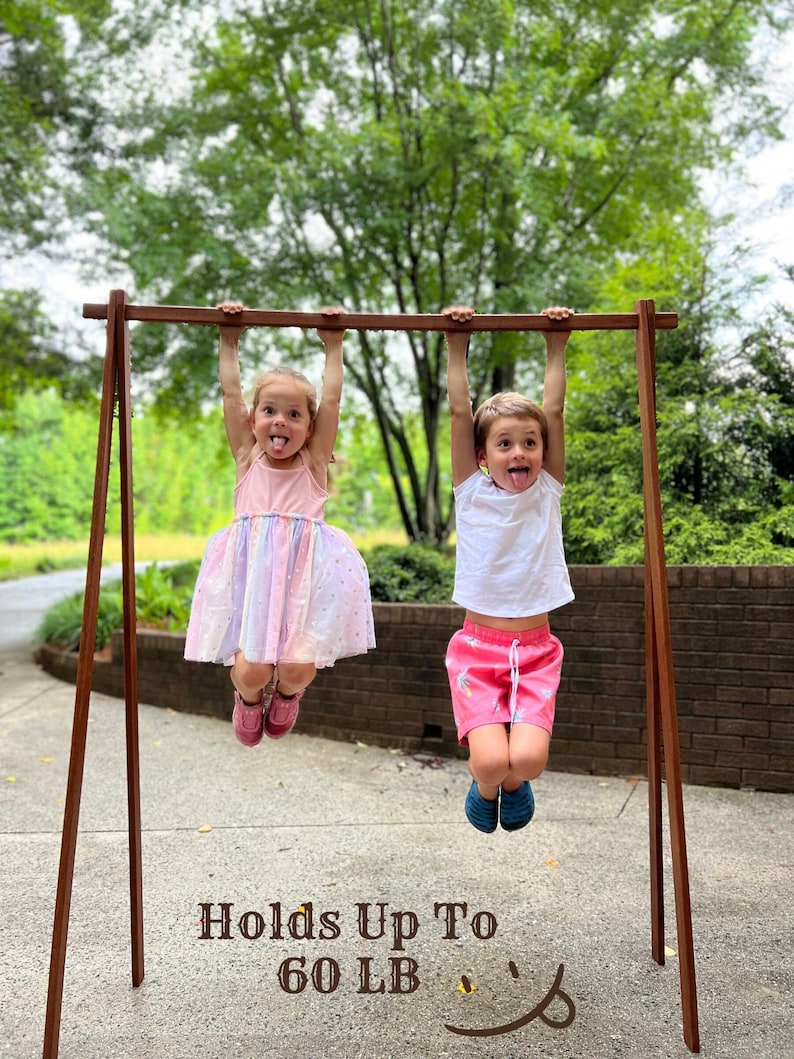 Ash wood clothing rack holding up to 60 lbs – strong enough for multiple items. Shown with two kids hanging, demonstrating stability and durability. Ideal for secure storage or display, combining function and style.