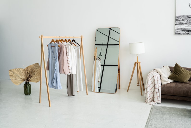 This  ash wood clothing rack features a smooth finish and simple, tool-free assembly. Perfect for organizing clothes in a modern, minimalist space. The neutral tones,mirror,and natural décor create a calming atmosphere, enhancing the room's elegance.