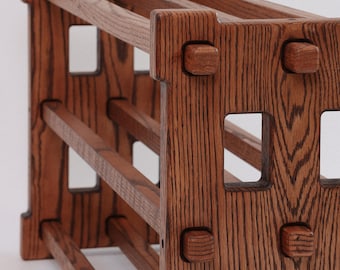 May include: A wooden shoe rack with three shelves. The rack is made of dark brown wood with a natural grain pattern. The shelves are supported by square wooden posts with rounded edges.