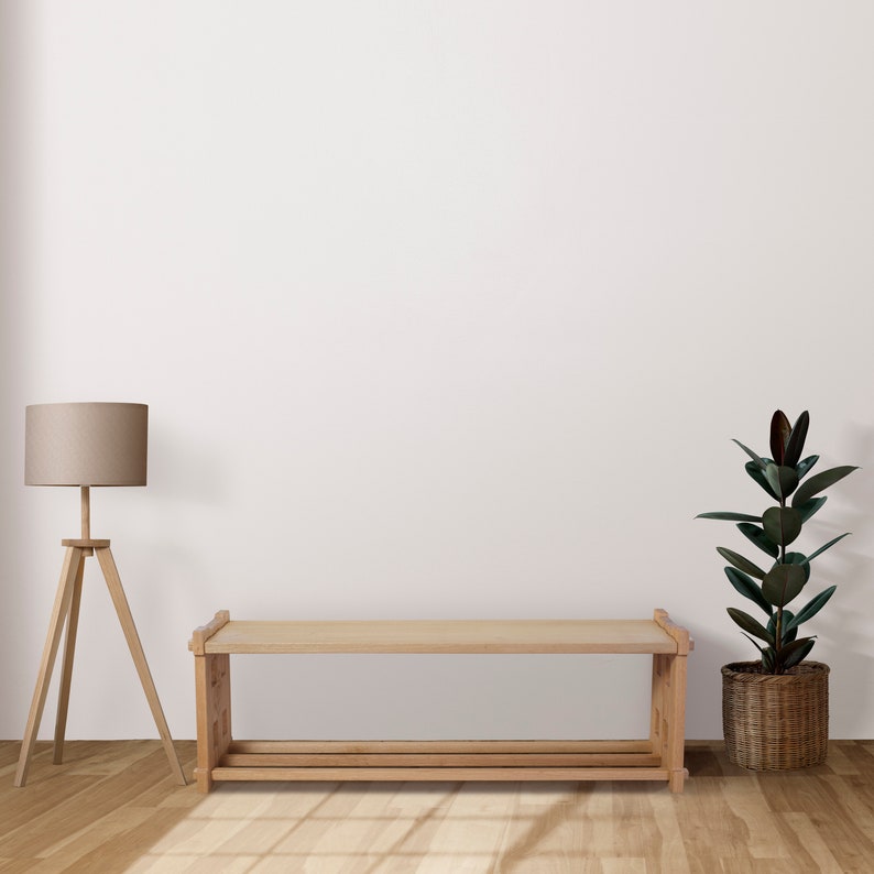 May include: A light-toned wooden bench featuring a rectangular top surface and a lower slatted shelf for storage. The bench has a simple, sturdy frame with vertical supports at each end, providing a clean and functional design for seating or storage.
