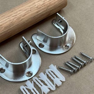May include: A wooden closet rod with two silver-colored rod holders, screws, and wall anchors. The rod is light brown and cylindrical. The rod holders are semi-circular with screw holes. The wall anchors are white.