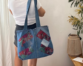 May include: A blue denim tote bag with patchwork details. The bag has a floral pattern and is made from recycled denim.