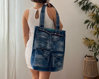 May include: A large blue denim tote bag with multiple pockets and a frayed edge. The bag is made from recycled denim and is a great way to carry your essentials.