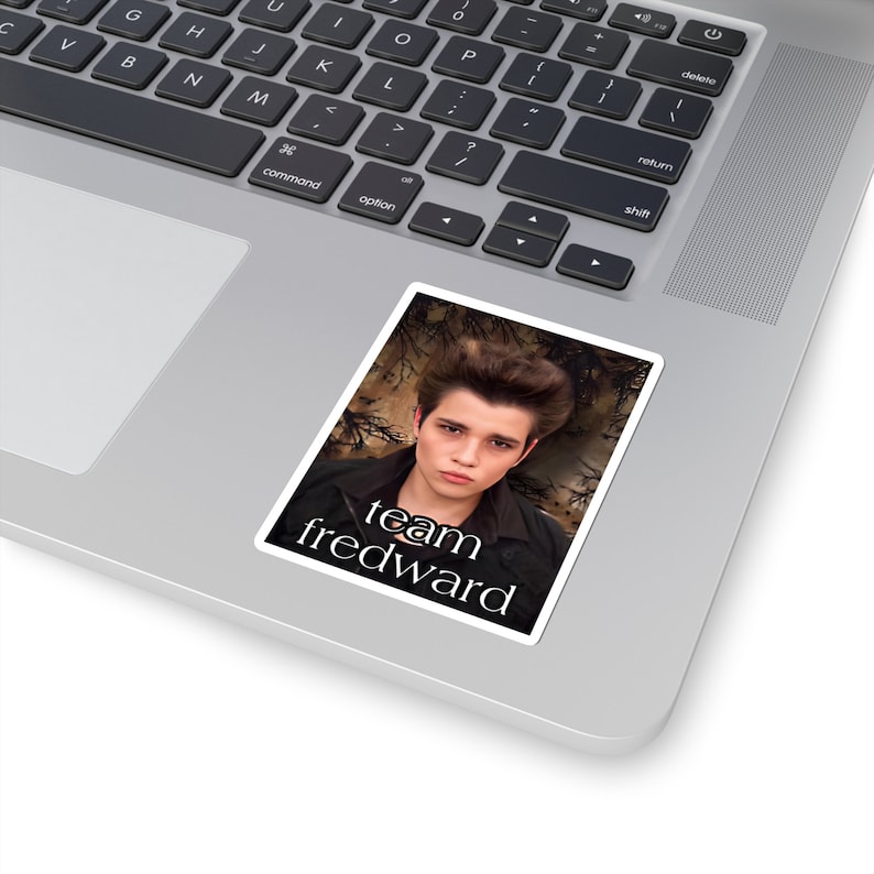 May include: A sticker featuring a portrait of a young man with dark hair and a black jacket. The text "team fredward" is printed below the portrait.