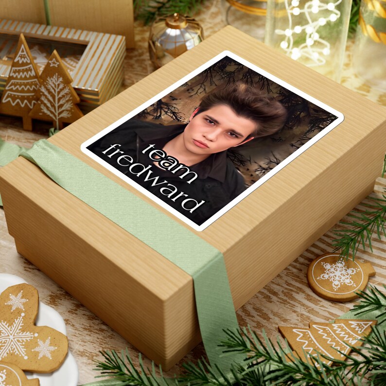 May include: A brown gift box with a green ribbon and a sticker featuring a photo of a young man with the text "team edward".